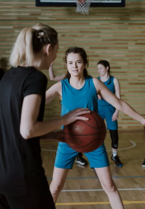Women engaged in a competitive basketball game indoors, showcasing teamwork and athleticism.