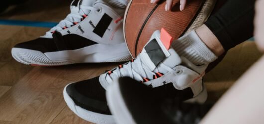 A close-up of athletes resting with a basketball, showcasing sneakers on a wooden court floor.