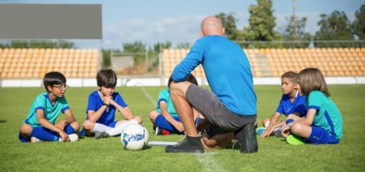 Group of kids receiving soccer coaching on a sunny day at a soccer field in Portugal.